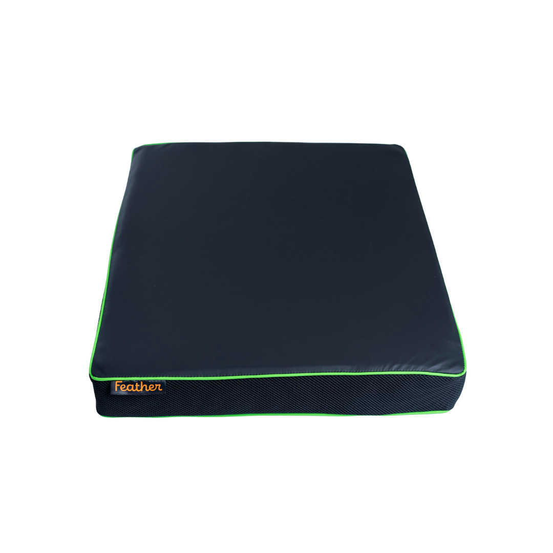 The Feather Portable Cushion is a rectangular, dark-colored memory foam cushion with green piping, an orange Feather label, a water-resistant cover, and a carry handle, shown against a white background.